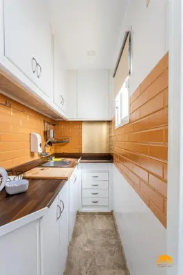 a small kitchen with white cabinets and wooden walls at Apartamento Encanto Gaditano con Terraza by Cádiz Time in Cádiz
