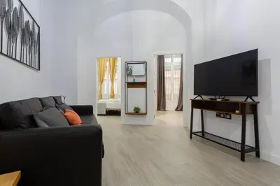 a living room with a black couch and a flat screen tv at CRUISE Adapted Apartment by Cadiz4Rentals in Cádiz