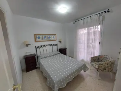 a bedroom with a bed and a chair and a window at Piso Bajo Guía in Sanlúcar de Barrameda