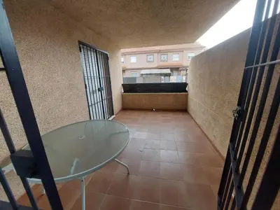 a room with a glass table and a balcony at Piso Bajo Guía in Sanlúcar de Barrameda