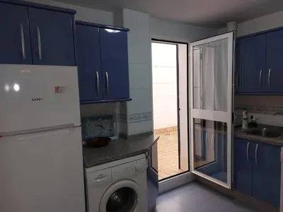 a kitchen with blue cabinets and a washing machine at Piso Bajo Guía in Sanlúcar de Barrameda