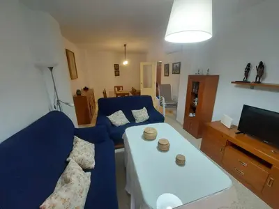 a living room with a blue couch and a white table at Piso Bajo Guía in Sanlúcar de Barrameda