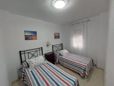 two beds in a room with white walls at Piso Bajo Guía in Sanlúcar de Barrameda