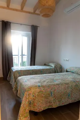 three beds in a room with a window at Apartamentos El Alcazar de Jerez in Jerez de la Frontera