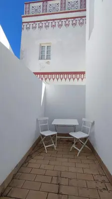 a patio with two chairs and a table and a building at APARTAMENTOS MINA4 tipo I in Cádiz