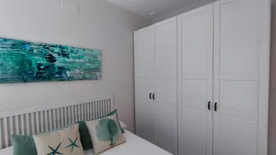 a bedroom with white cabinets and a bed with pillows at APARTAMENTOS MINA4 tipo I in Cádiz