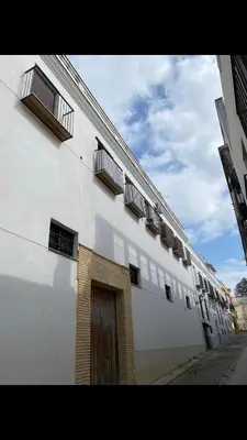 a white building with windows and a door on a street at Casa trillo in Sanlúcar de Barrameda