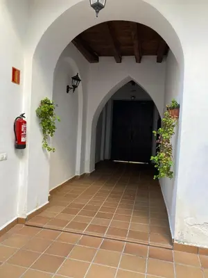 an archway with plants on the wall and a black door at Casa trillo in Sanlúcar de Barrameda