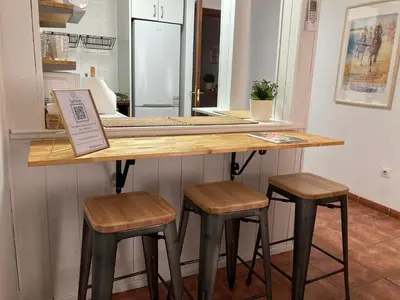a counter with two stools and a table in a kitchen at Casa trillo in Sanlúcar de Barrameda