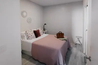 a white bedroom with a bed and a table at Eva Recommends Capilla de la Jura en Jerez in Jerez de la Frontera