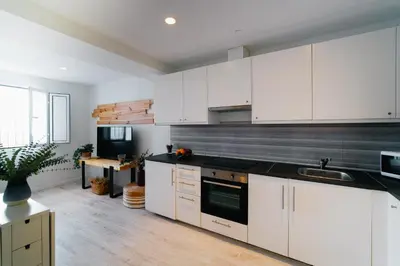 a kitchen with white cabinets and a black counter top at Eva Recommends Capilla de la Jura en Jerez in Jerez de la Frontera