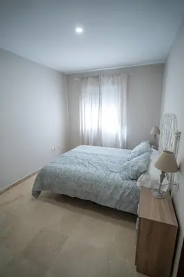 a bedroom with a bed and a table with two lamps at Las Palomas 15 in Sanlúcar de Barrameda