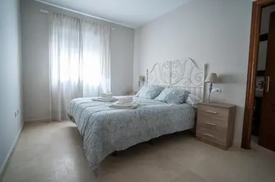 a bedroom with a bed and a dresser and a window at Las Palomas 15 in Sanlúcar de Barrameda