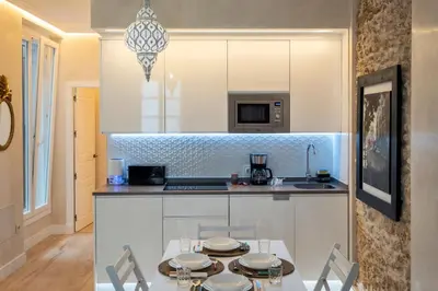 a kitchen with a table with chairs and a counter top at Gadir Suites in Cádiz
