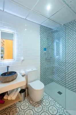 a bathroom with a toilet and a glass shower at Gadir Suites in Cádiz