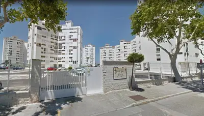 a white fence in front of tall white buildings at ESTUDIO BLEGAMAR TERRAZA - Playa, WiFi y Aparcamiento in El Puerto de Santa María
