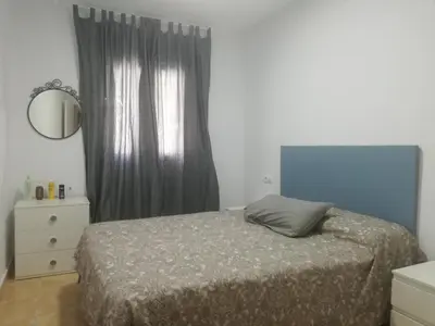 a bedroom with a bed and a mirror and a window at Apartamento Conil San Diego de Alcalá in Conil de la Frontera