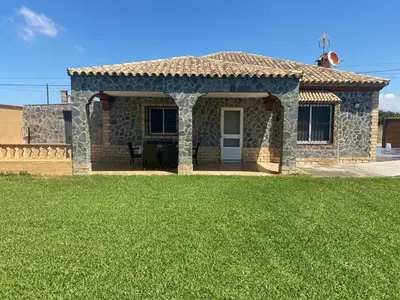 a stone house with a porch and a lawn at Casa Silvia in Cádiz