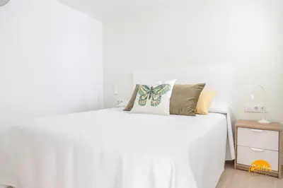 a white bedroom with a white bed and a nightstand at Villalobos by Cadiz Time in Cádiz