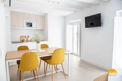 a kitchen and dining room with a wooden table and yellow chairs at Villalobos by Cadiz Time in Cádiz