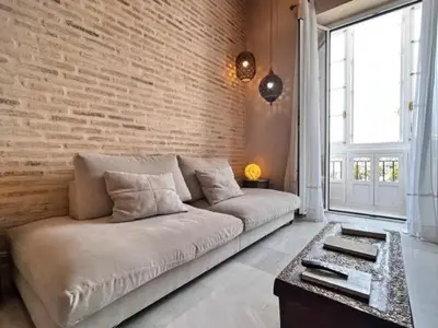 a living room with a couch and a brick wall at innCádizPalacio Conde Casa-Brunet in Cádiz