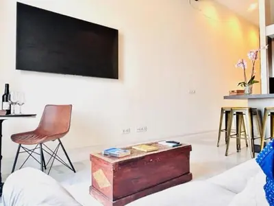 a living room with a tv and a chair and a table at innCádizPalacio Conde Casa-Brunet in Cádiz