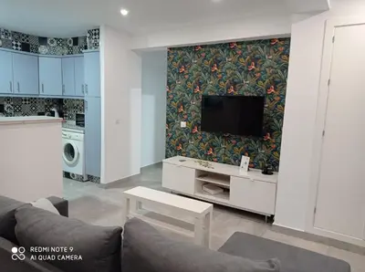 a living room with a couch and a tv on a wall at Love & Dream Beach Grupo AC Gestion in Cádiz