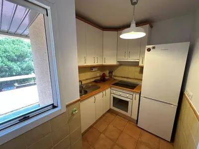 a kitchen with a white refrigerator and a window at En la zona más tranquila del Novo Sancti Petri in Chiclana de la Frontera