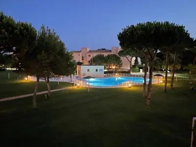 a swimming pool with trees in a park at night at En la zona más tranquila del Novo Sancti Petri in Chiclana de la Frontera