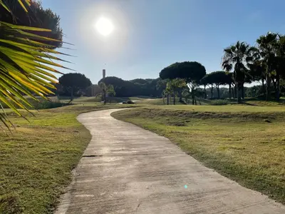 a dirt road in a park with the sun in the sky at En la zona más tranquila del Novo Sancti Petri in Chiclana de la Frontera