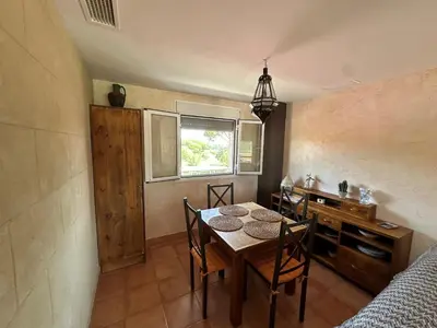 a dining room with a table and chairs and a bed at En la zona más tranquila del Novo Sancti Petri in Chiclana de la Frontera