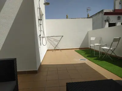 a balcony with chairs and a table on a building at ÁTICO EN EL CENTRO, terraza 20 m2, garaje, Wi-Fi, AC in Sanlúcar de Barrameda