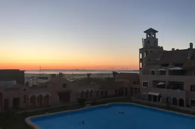 a sunset view of a building with a swimming pool at Apartamento S. Fernando bahia sur in San Fernando