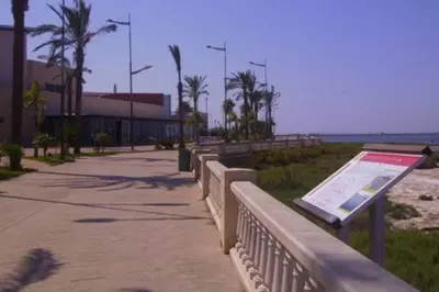 a bench with a sign on it next to the beach at Apartamento S. Fernando bahia sur in San Fernando