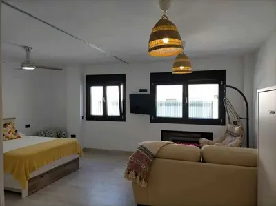 a bedroom with a couch and a bed and windows at Acogedor apartamento en la playa de Cádiz in Cádiz