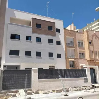 a tall white building with a fence in front of it at Acogedor apartamento en la playa de Cádiz in Cádiz