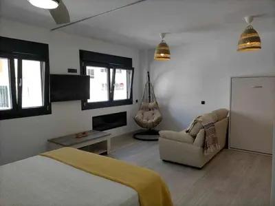 a bedroom with a bed and a couch and a chair at Acogedor apartamento en la playa de Cádiz in Cádiz