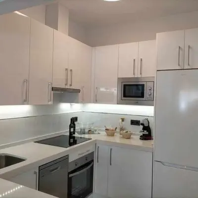 a white kitchen with a sink and a refrigerator at Acogedor apartamento en la playa de Cádiz in Cádiz