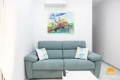a living room with a blue couch and a painting at Casa Patio La Viña by Cadiz Time in Cádiz