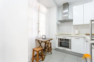 a kitchen with white cabinets and a wooden table at Sagasta 1750 by Cadiz Time in Cádiz
