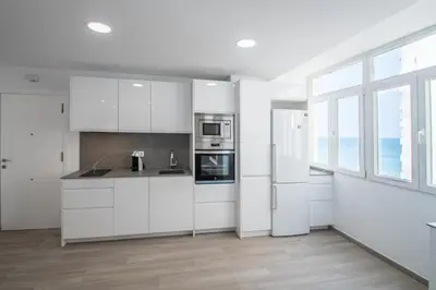 a white kitchen with white appliances and windows at Nuevo Mirandilla Apartment - Cadiz Beach in Cádiz