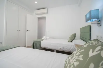 a bedroom with two beds and a tv on the wall at Nuevo Mirandilla Apartment - Cadiz Beach in Cádiz