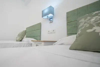 a bedroom with two beds and a tv on the wall at Nuevo Mirandilla Apartment - Cadiz Beach in Cádiz