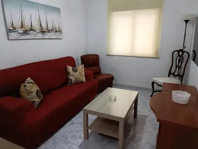 a living room with a red couch and a table at Apartamento Candari Playa en Cadiz in Cádiz