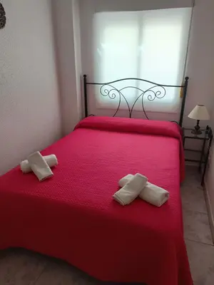a red bed with two white pillows on it at Apartamento Candari Playa en Cadiz in Cádiz