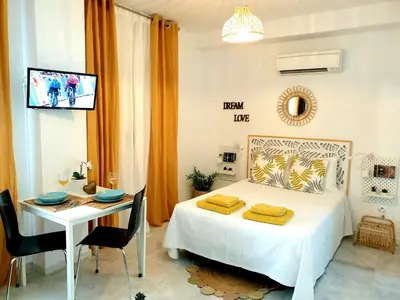 a bedroom with a bed and a table and a tv at Sherryflat Estudio- Parking, in Jerez de la Frontera