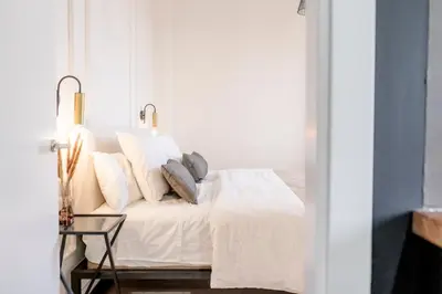 a bedroom with a bed with white sheets and pillows at Suites Alfonso X in Jerez de la Frontera