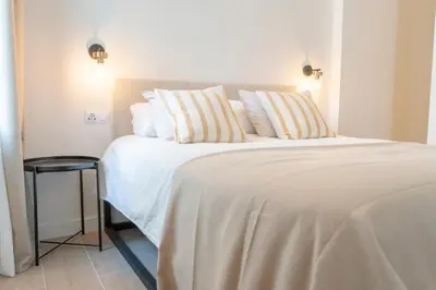 a bedroom with a large bed with white sheets and pillows at Suites Alfonso X in Jerez de la Frontera