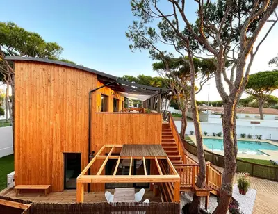 a wooden house with a picnic table and a pool at Apartamentos Biopasivos Living Pura Madera in Chiclana de la Frontera