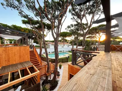 an outdoor patio with a wooden deck and a swimming pool at Apartamentos Biopasivos Living Pura Madera in Chiclana de la Frontera